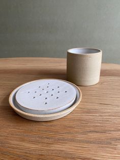 a white cup and saucer sitting on top of a wooden table next to each other