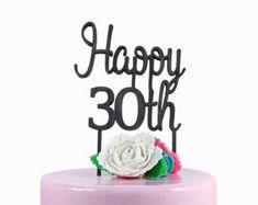 a pink cake topped with a white flower and the words happy 30th on it's top