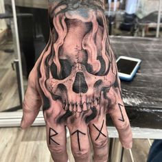 a man's hand with a skull and arrows tattooed on the inside of it