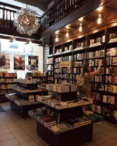 a woman standing in front of a book store filled with lots of books on shelves