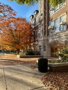 an apartment building with autumn leaves on the ground