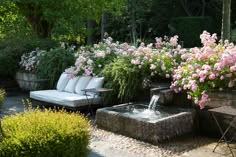 an image of a garden with flowers and plants in the foreground, and a couch on the other side