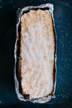 an uncooked cake sitting on top of a pan covered in tin foil and sprinkled with powdered sugar