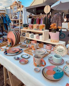 a table topped with lots of colorful plates and cups next to each other on top of a white table cloth