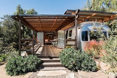 an airstream sits in the middle of a wooded area with stairs leading up to it