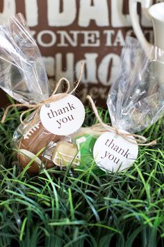 two thank you bags sitting on top of grass next to a coffee cup and mug