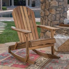 a wooden rocking chair sitting on top of a rug next to a stone wall and table