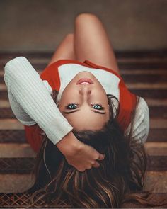 a woman laying down on the ground with her head resting on her hands and eyes open