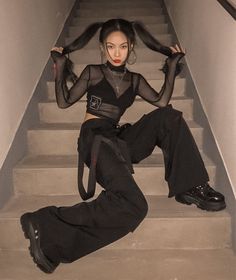 a woman is sitting on the stairs with her hair tied back and wearing black pants