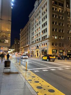 a city street at night with people walking on the sidewalk and cars driving down the road