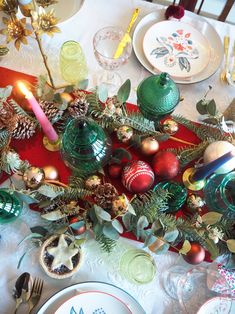 the table is set with christmas decorations and plates, silverware and candlesticks