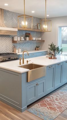 Light blue and white cottagecore kitchen with a vintage island, farmhouse sink, herringbone backsplash, and warm lighting. Blue Theme Kitchen, Kitchen Blue Countertops, Grandmillenial Style Kitchens, Blue Kitchen Cabinets White Countertops, Blue And Rose Gold Kitchen, Light Blue Kitchen Decor, Light Teal Kitchen, Kitchen With Teal Accents, Light Blue Backsplash Kitchen