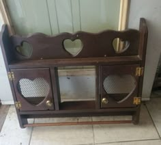 an old wooden cabinet with hearts cut out of the front and sides, sitting on a tile floor