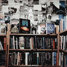 a bookshelf filled with lots of books next to a wall covered in pictures