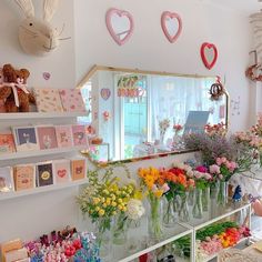 a flower shop filled with lots of flowers and stuffed animals on the wall next to it