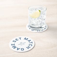 two coasters sitting on top of a wooden table next to a glass filled with water