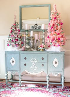 a pink christmas tree sitting on top of a blue dresser in front of a mirror