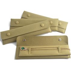 three pieces of tan leather with buttons on each side and a green stone in the middle