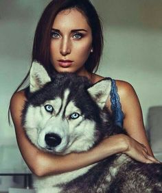 a woman is holding a husky dog in her arms and looking at the camera with an intense look on her face