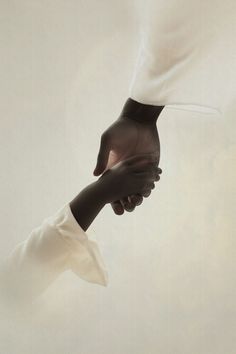 two black hands holding each other's hand in front of a white background with light coming through it