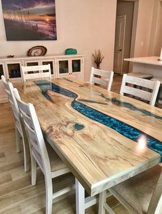 a wooden table topped with white chairs and a blue river design on top of it