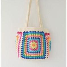 a multicolored crocheted bag hanging on a wall next to a pair of scissors