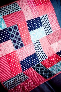 a red, white and blue patchwork quilt on a black cloth with polka dots