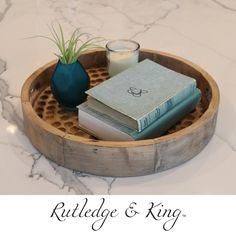 a wooden tray with books, candle and air plant on it that says ruttledge & king