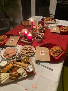 a table topped with lots of food on top of a white table cloth next to a lit candle