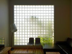 two chairs and a table in front of a large window with glass blocks on the wall