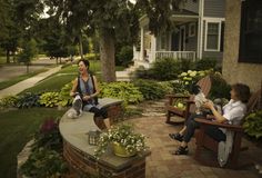 two women sitting on wooden benches in front of a house and one woman holding a cat