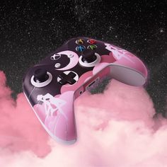 a video game controller flying through the air with pink clouds around it and stars in the background