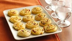 a plate full of cookies and wine glasses on a table with an orange napkin in the background