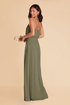 a woman in a long green dress with her back to the camera and holding flowers