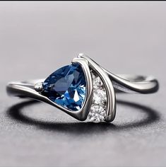 a blue and white diamond ring sitting on top of a gray surface with diamonds around it