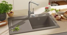 a kitchen sink sitting on top of a counter next to some bread and other food