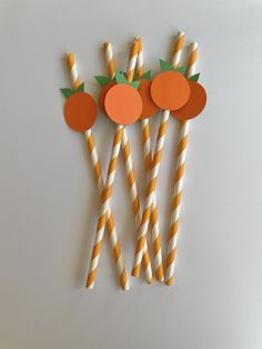 three orange and white striped straws with apples on them, one is made out of paper