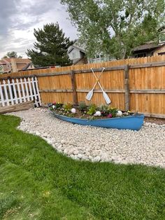 a blue boat sitting in the middle of a yard next to a fence and grass