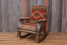 an old rocking chair on a wooden floor in front of a wall with wood planks