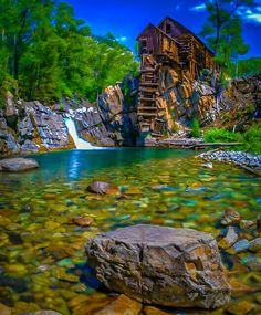 a wooden structure sitting on top of a rocky hillside next to a river filled with water