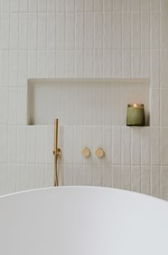 a white bath tub sitting next to a wall mounted candle