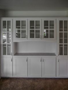 a kitchen with white cupboards and shelves in it's center area, along with carpeted flooring