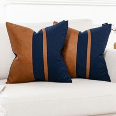 two brown and blue pillows sitting on top of a white couch