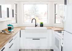 a kitchen with white appliances and wooden counter tops next to a window overlooking the street