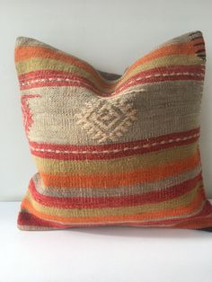 an orange and brown striped pillow sitting on top of a white table