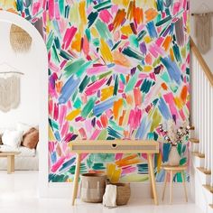 a colorful wallpaper in a living room next to a stair case and table with vases on it