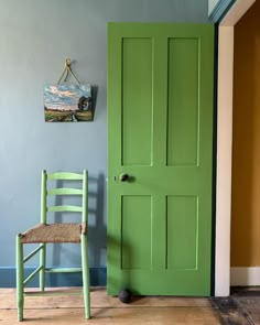 a green door with a chair next to it in front of a painting on the wall