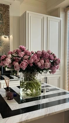 a vase filled with pink flowers sitting on top of a marble topped table next to a mirror