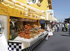 the people are walking down the street by the food stand