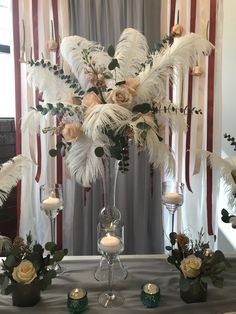 an arrangement of flowers and candles on a table in front of a curtained window